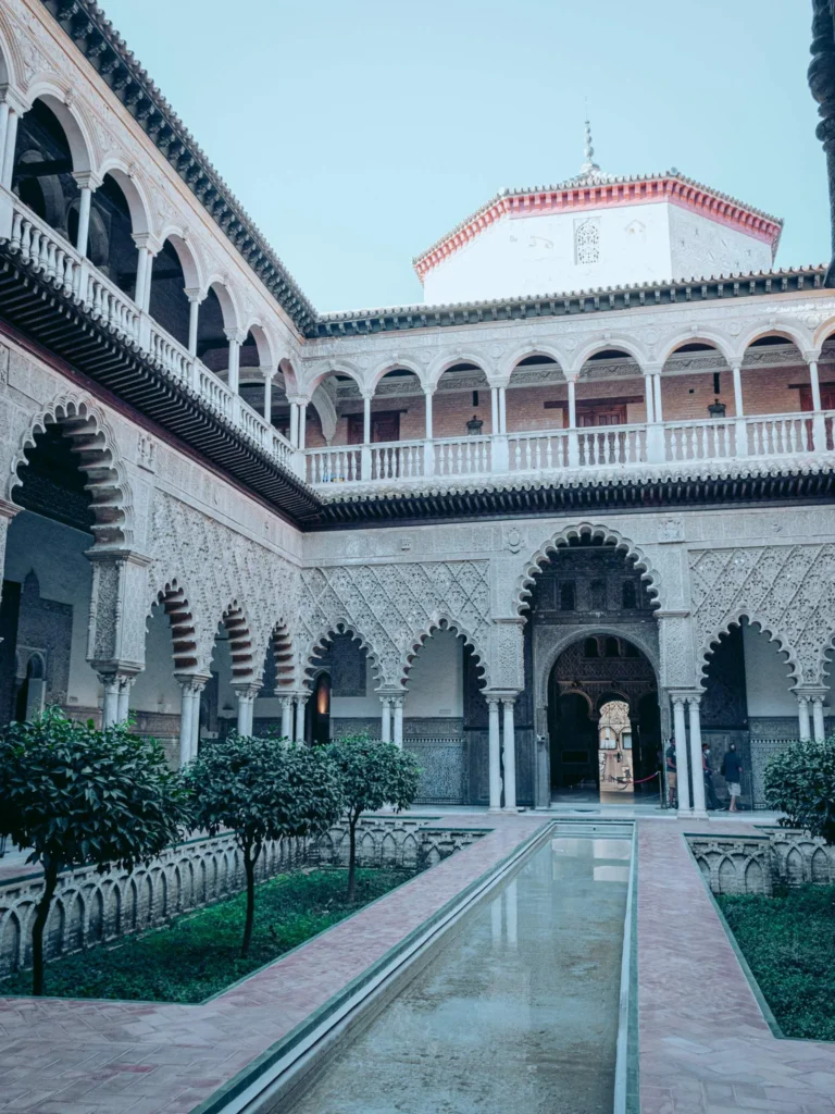 Cour intérieure du palais de l'Alcazar à Séville, architecture mudéjare avec arcades sculptées et bassin central, prise en octobre 2022.
