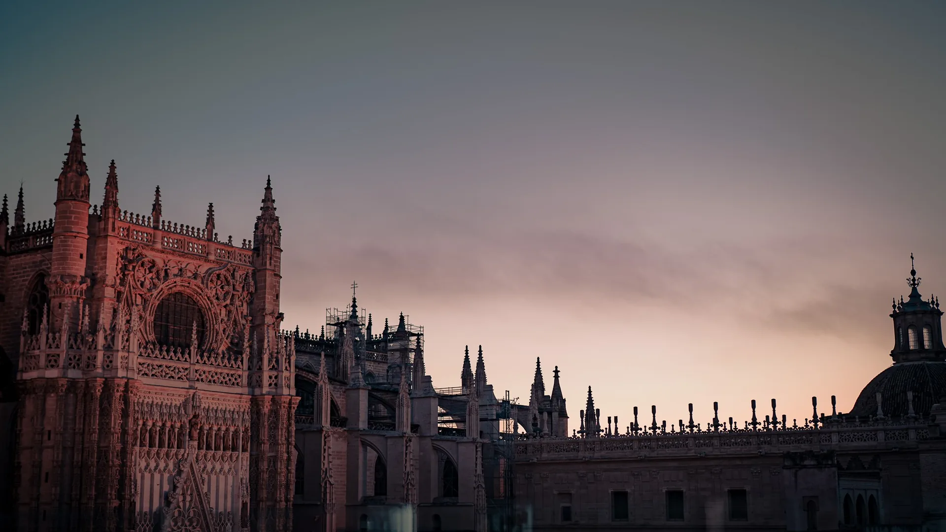 Façade et toits de la cathédrale de Séville photographiés depuis un rooftop au coucher du soleil, sans présence humaine visible.