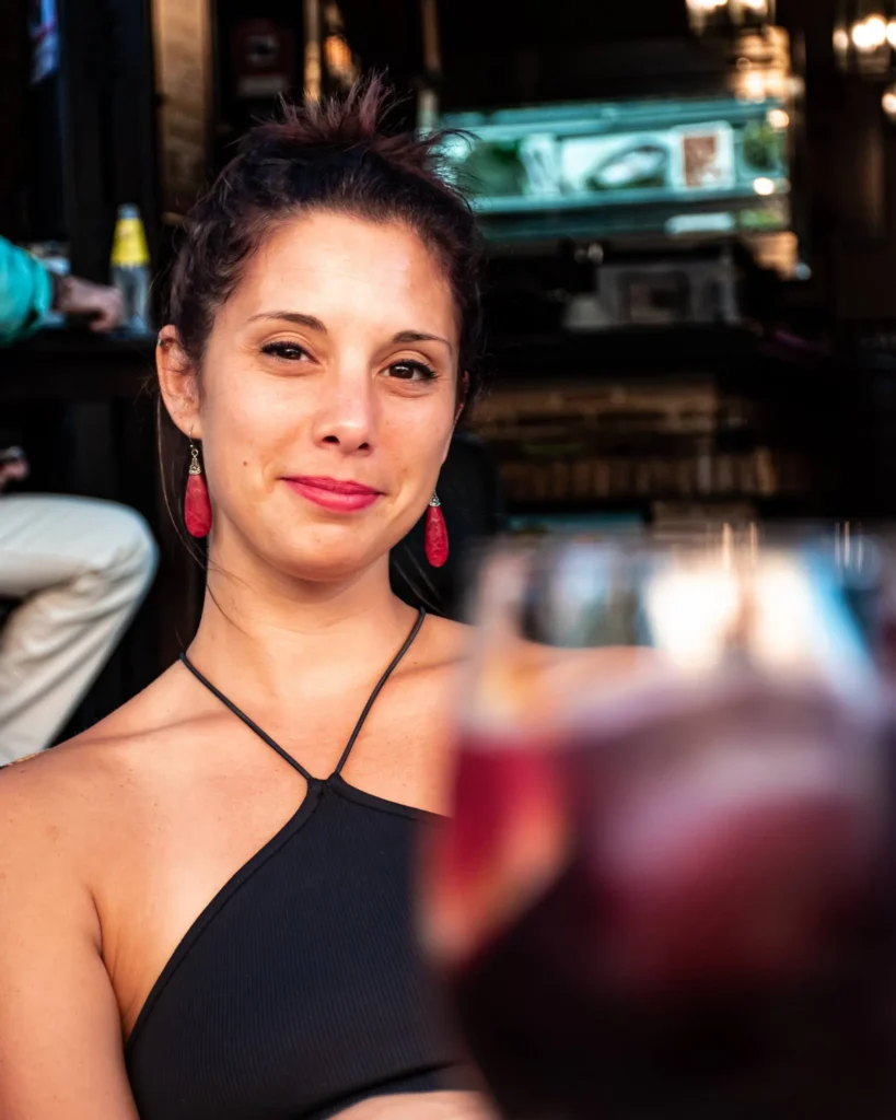 Caroline assise en terrasse d'un bar à Séville, un verre de sangria au premier plan.