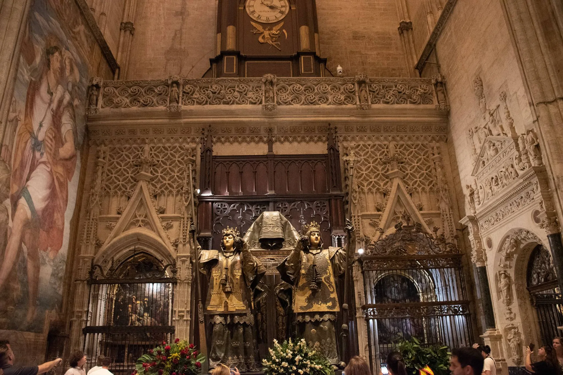 Tombeau monumental de Christophe Colomb dans la cathédrale de Séville, entouré de visiteurs et d'une architecture gothique richement décorée.