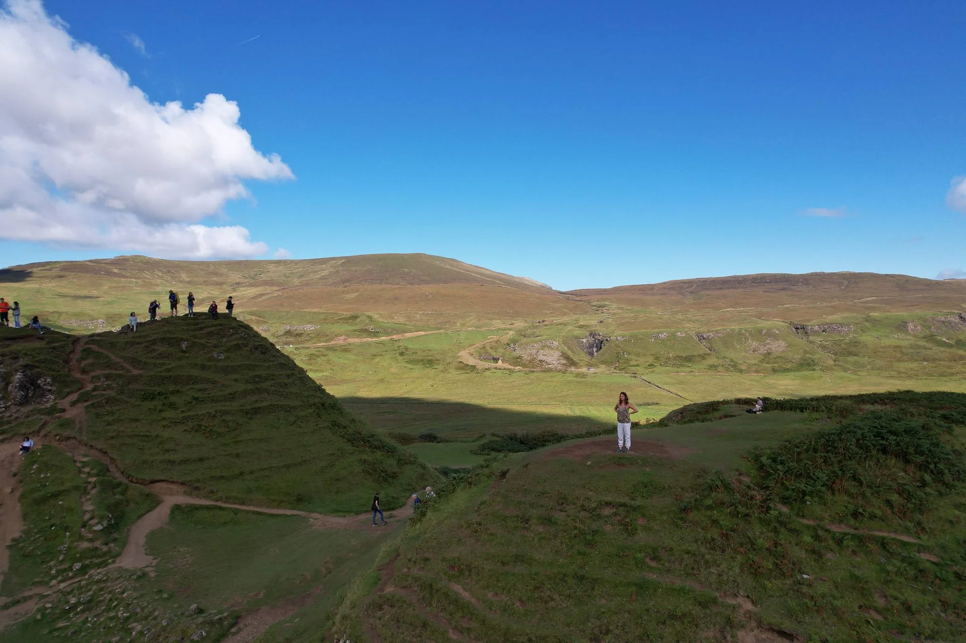 Fairy Glen on the Isle of Skye with rolling green hills and visitors under a blue sky