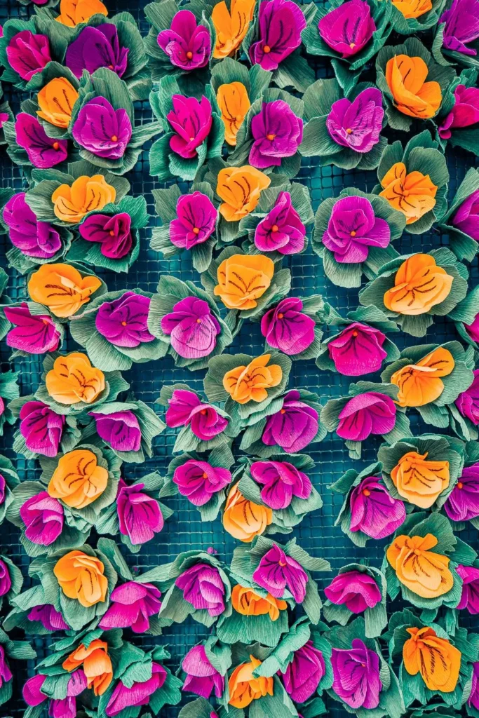 Décorations florales en papier coloré, typiques du Festival des Tabuleiros à Tomar, disposées en motifs répétitifs sur un support grillagé.