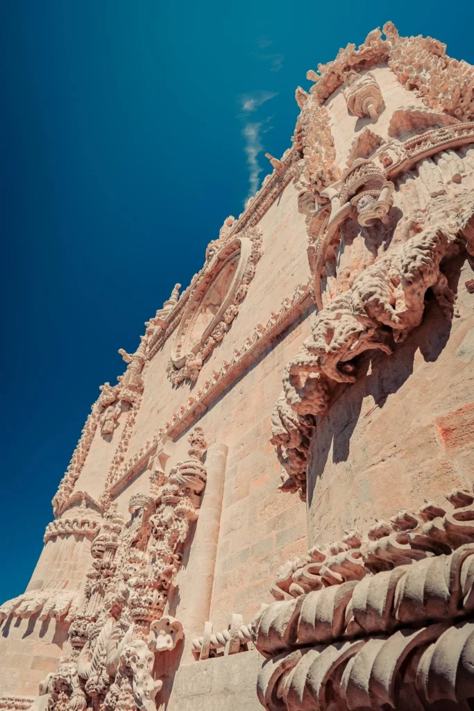Façade richement ornée du Couvent de l'ordre du Christ à Tomar sous un ciel bleu, mettant en valeur l'architecture manuéline du monument historique.