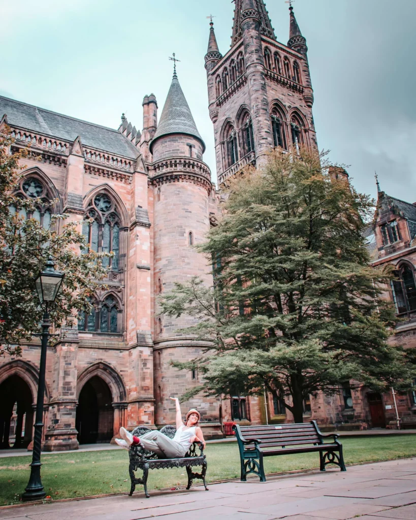 Caroline lying on a bench in front of the gothic architecture