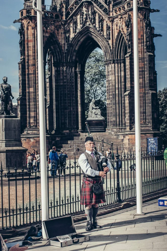 Xavier plays the bagpipes in a Scottish kilt in front of the Scott Monument in Edinburgh