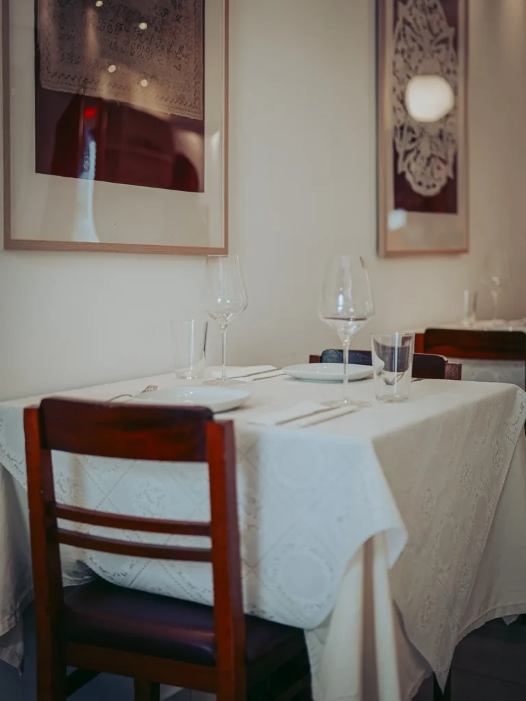Table set with white tablecloths and wine glasses in a restaurant in Tavira, Algarve, Portugal, calm atmosphere and textile wall decor.