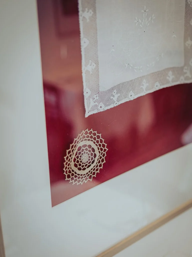 Detail of a white lace placemat framed, displayed against a red background in an interior, probably at the Case de Pasto restaurant in Tavira, Algarve.