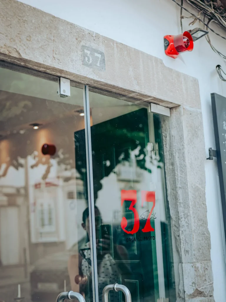Glass entrance of the restaurant 37 Casa de Pasto in Tavira, Algarve, with the number 37 displayed above the door and on the glass.