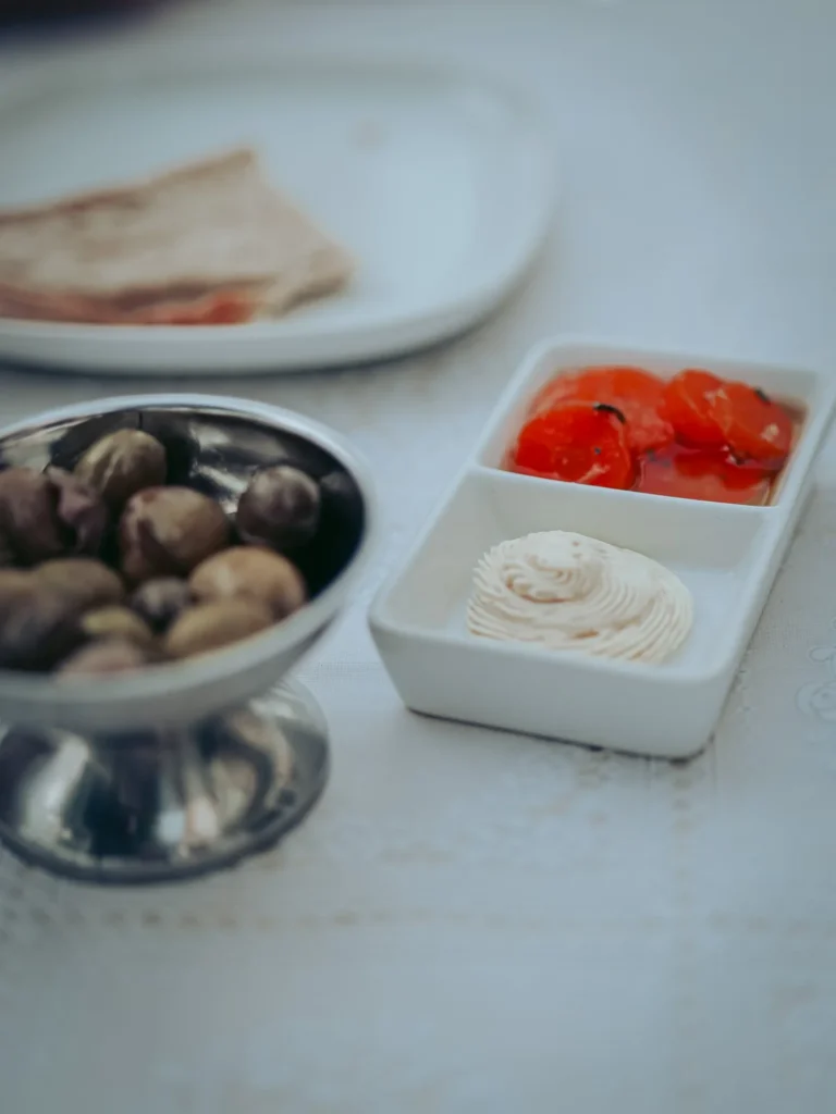 Assortment of olives, candied carrots, and butter (the Portuguese cutlery) arranged on a restaurant table in Tavira, Algarve.