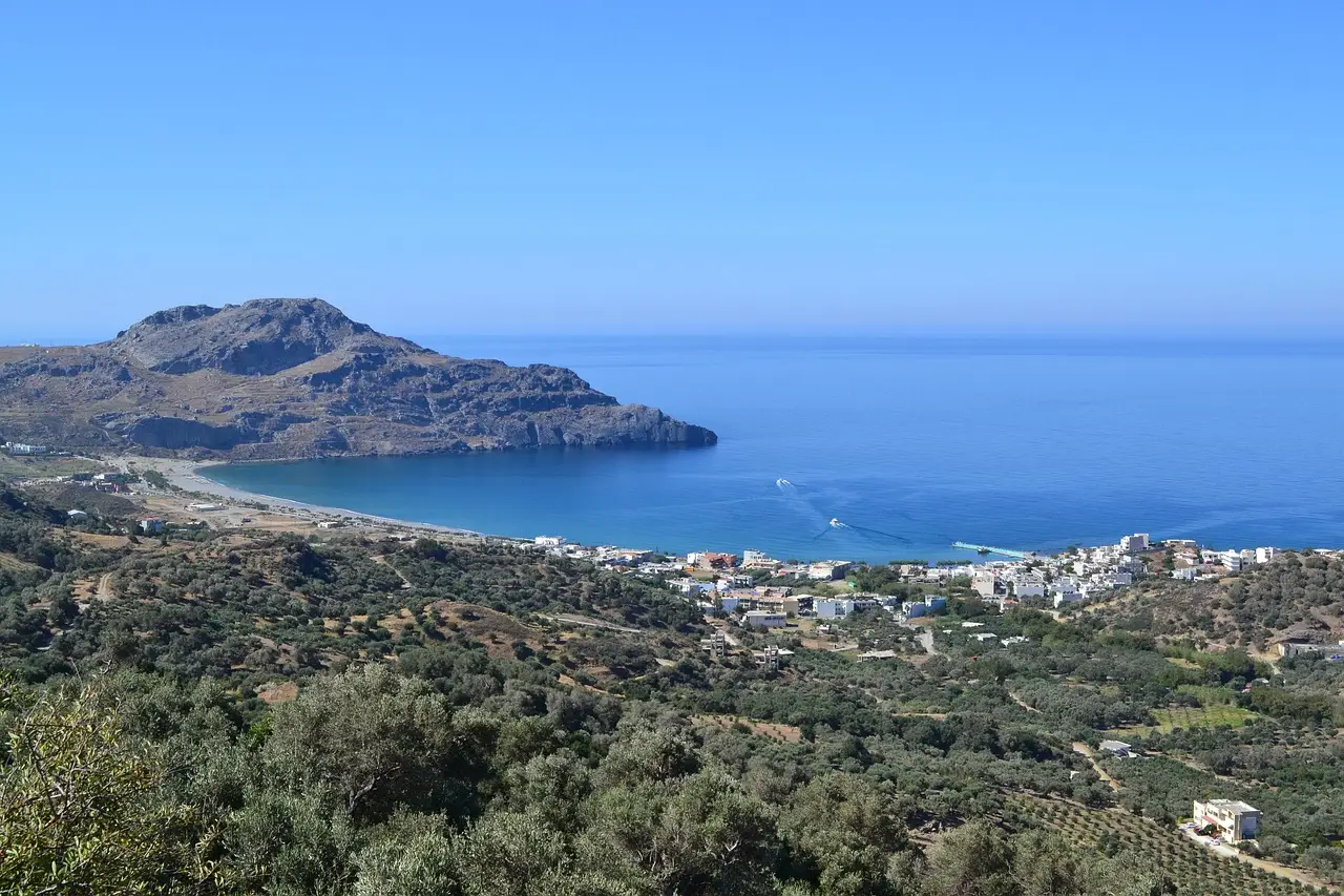 Panoramic view of Plakias Bay in Crete, turquoise sea and mountains under a clear blue sky.