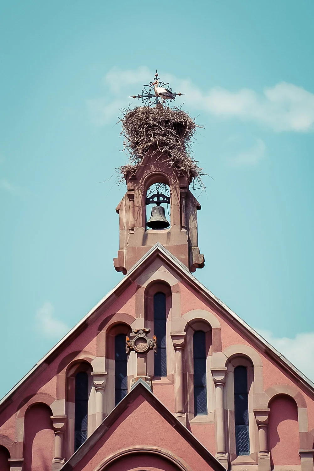 Facade of the Saints-Pierre-et-Paul church in Eguisheim with a stork nest on top of the bell tower