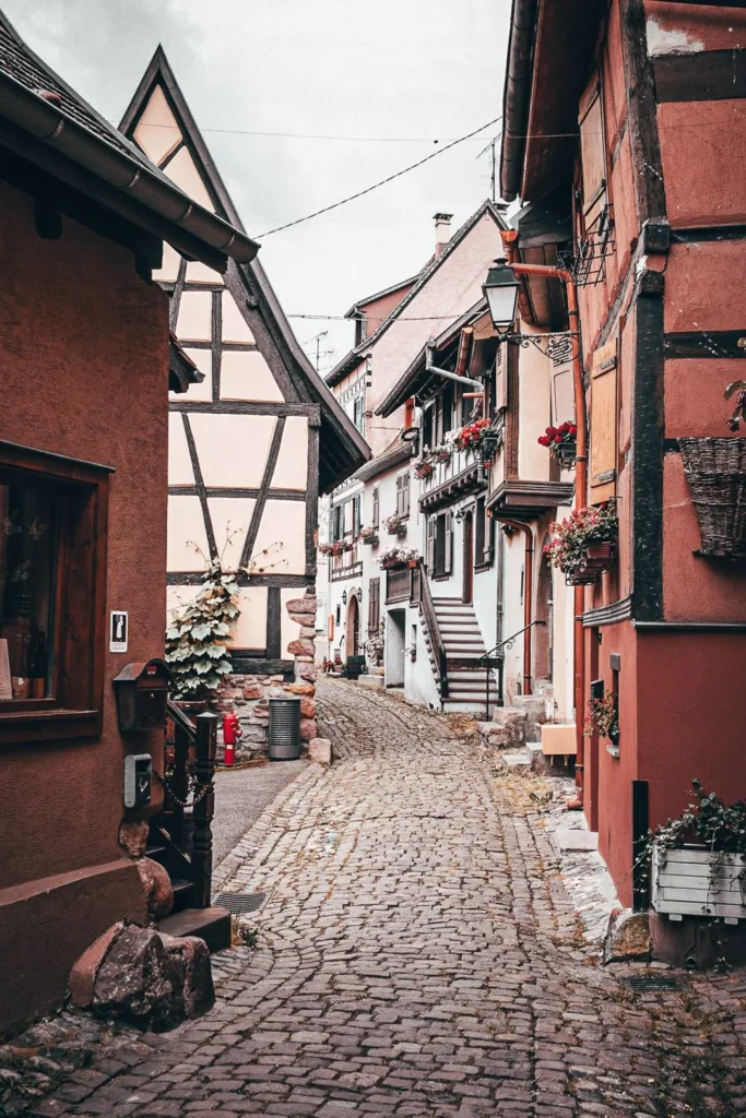 Cobblestone alley lined with traditional half-timbered houses in Eguisheim, circular medieval village