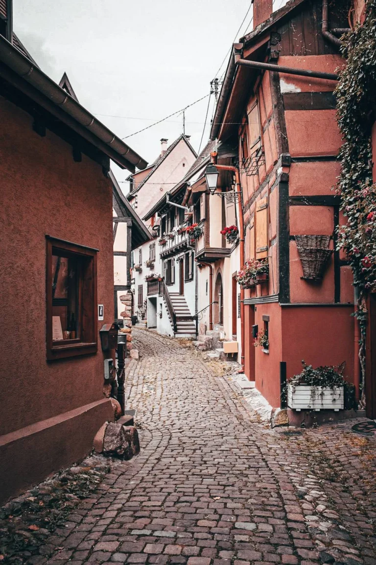 Cobblestone alley lined with traditional half-timbered houses in Eguisheim, atmosphere of the Most Beautiful Villages of France