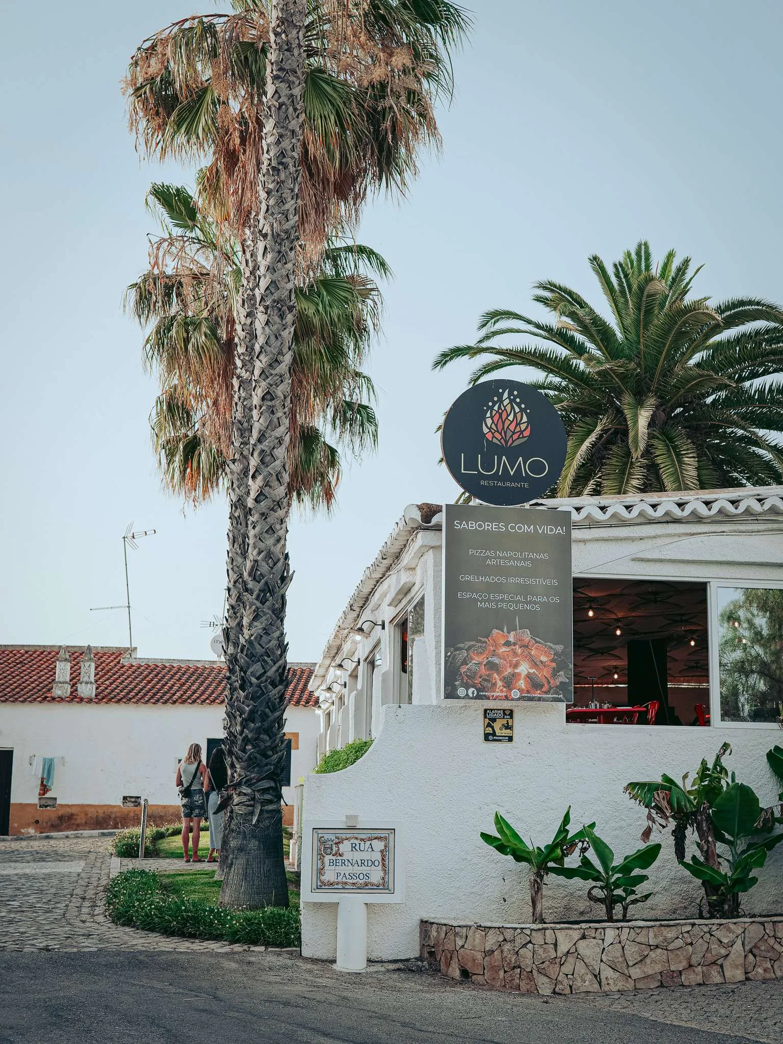Facade of the Lumo restaurant in Tavira, Algarve, with palm trees and a terrace visible in summer.