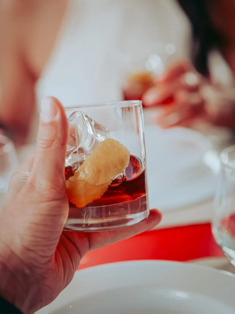 Main holding a glass of pink martini with ice and citrus zest on a set table at Lumo restaurant in Tavira, Algarve, in June.