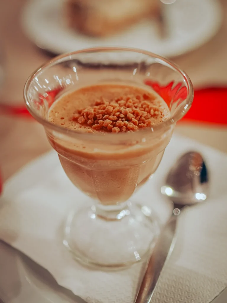 Caramel mousse verrine with praline crunch, served on a table at Lumo restaurant in Tavira, Algarve.