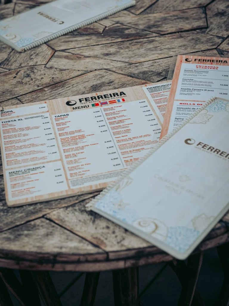 Menus of the O Ferreira restaurant placed on a wooden table in Tavira Island, Algarve, Portugal, in June 2026.
