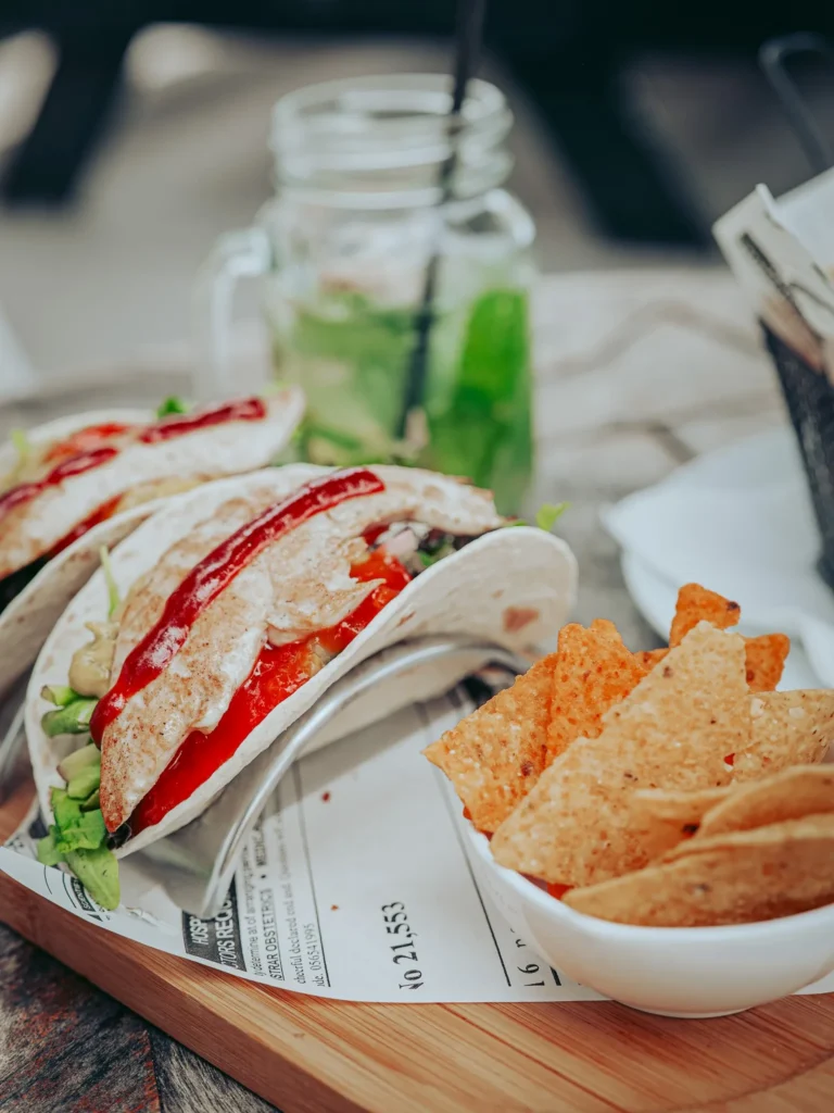 Chicken tacos served with corn chips and ginger-mint lemonade on a wooden table at O Ferreira, Tavira Island, Algarve, Portugal in June.