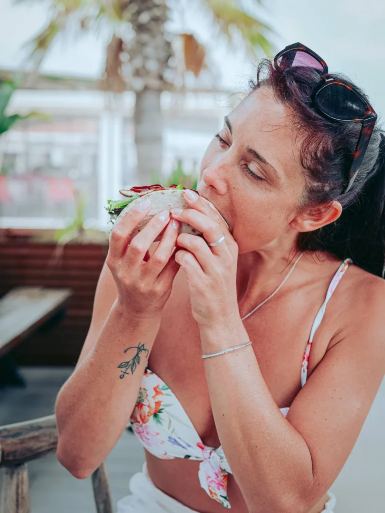 Caroline is enjoying a chicken taco on the terrace under the palm trees on the island of Tavira, Algarve, on a summer day.