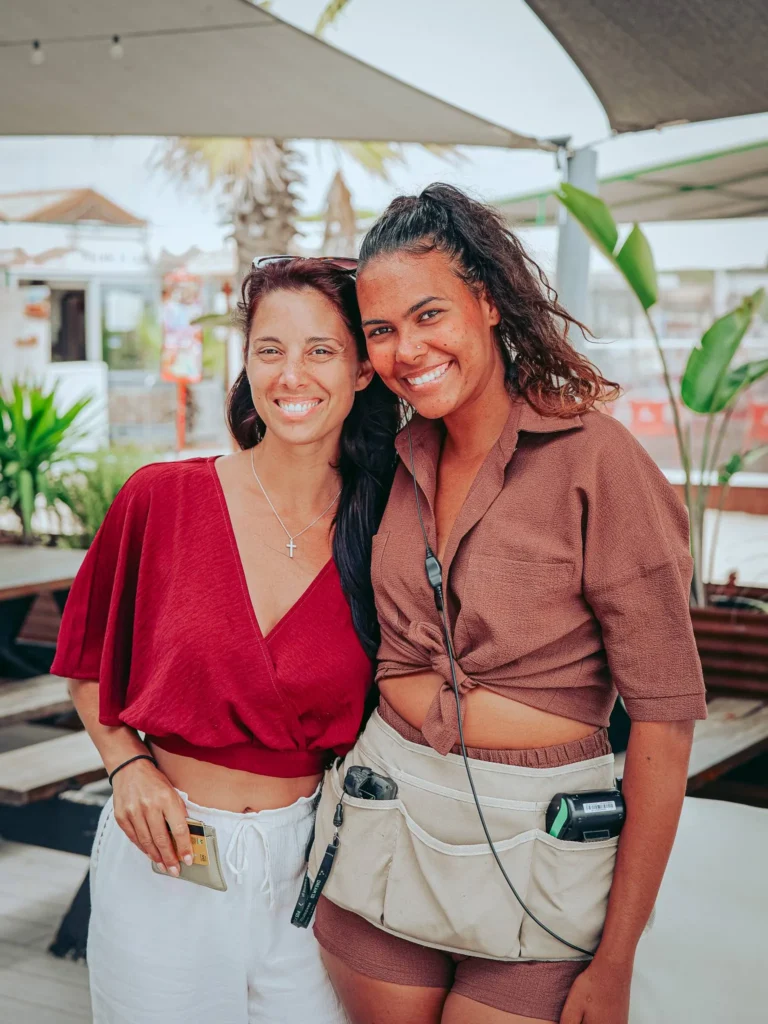 Caroline poses with an employee in front of a shaded terrace on the island of Tavira, in the Algarve, on a summer day.