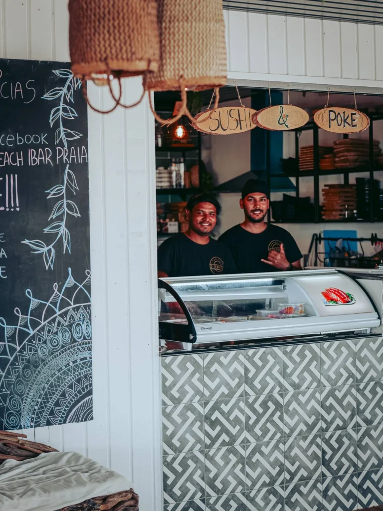 Two employees behind the counter of a sushi and poke bar on the island of Tavira, Algarve, beach decor and summer atmosphere.
