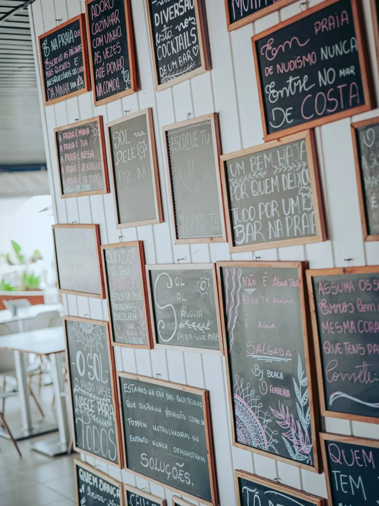 Wall decorated with multiple chalkboards featuring quotes written in chalk in a bar or restaurant on the island of Tavira, Algarve, Portugal, with a summery and relaxed atmosphere.