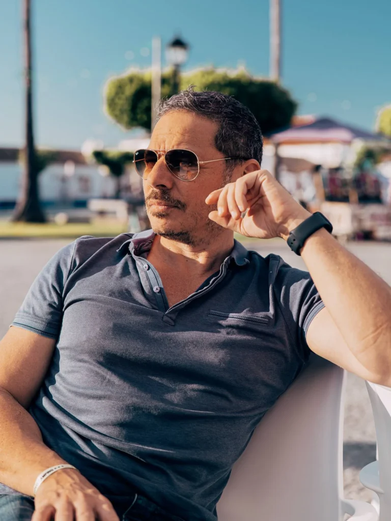 Xavier sitting on a terrace in Porto Covo under the sun, wearing sunglasses and a smartwatch.