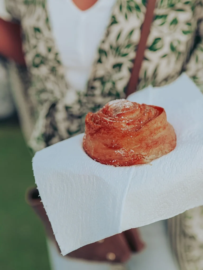 Portuguese pastry placed on a paper napkin, held by a person in the background in Vila Nova de Milfontes in June.