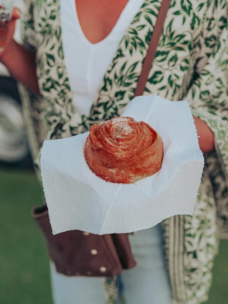 Caroline is holding a Portuguese pastry on a paper towel, dressed in a leaf-patterned kimono in Vila Nova de Milfontes in June.