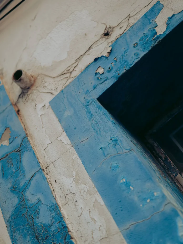 Detail of an old wall with peeling blue paint, typical of the facades in Alentejo at Vila Nova de Milfontes, photographed in June.