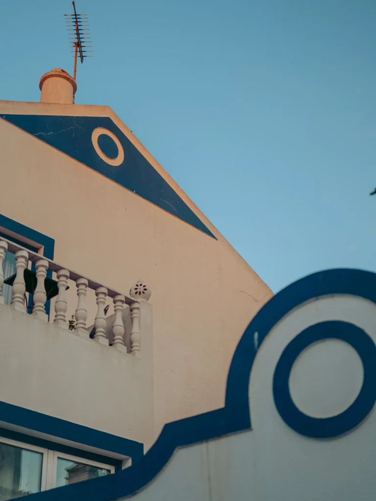 Facade of a typical Alentejo house in Vila Nova de Milfontes, with blue and white patterns and a balustrade, under a clear sky.