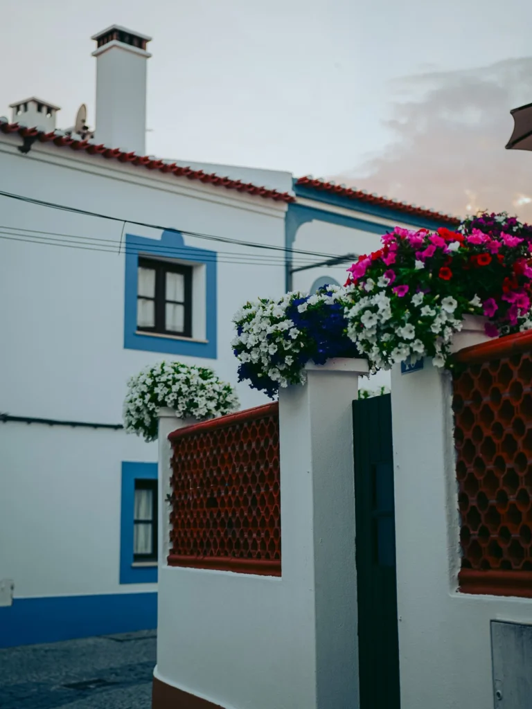 Facade of a white house with typical blue frames of Alentejo, with flower boxes, in Vila Nova de Milfontes