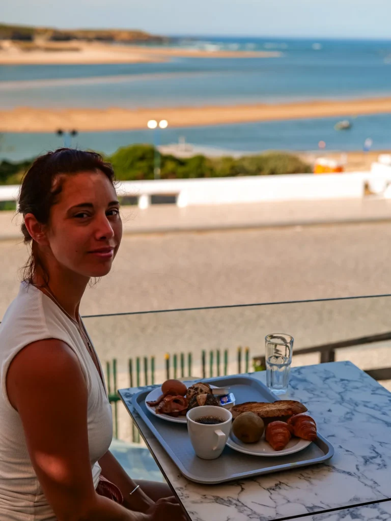 Caroline has her breakfast on the terrace of the Duna Parque Hotel with a view of the beach and the estuary in Vila Nova de Milfontes, under the June sun.