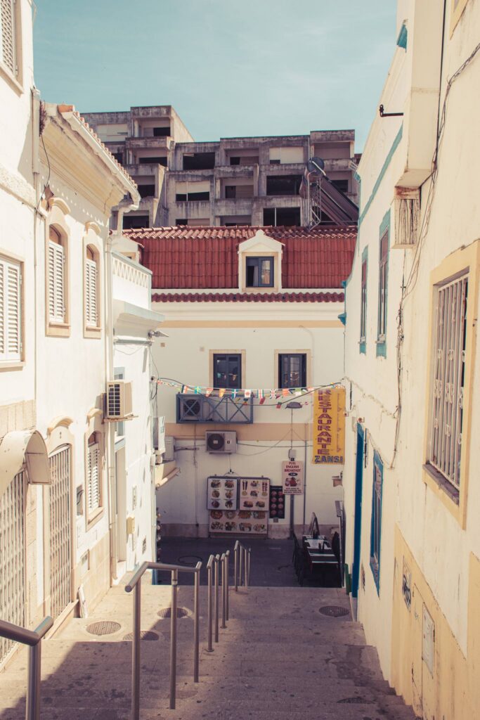 Sloping alley in Albufeira with an abandoned building in the background