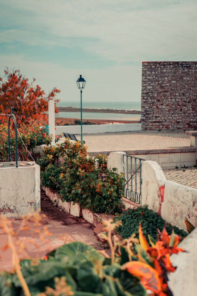 Flowering garden with ancient well and lime-washed walls in Cacela Velha, Algarve