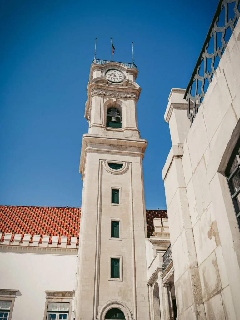 Clock tower of the University of Coimbra under a blue sky, iconic architecture of the historic center.