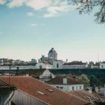 View of the rooftops of Coimbra with a historic dome building in the background under a partially cloudy sky, in Portugal at the end of March.