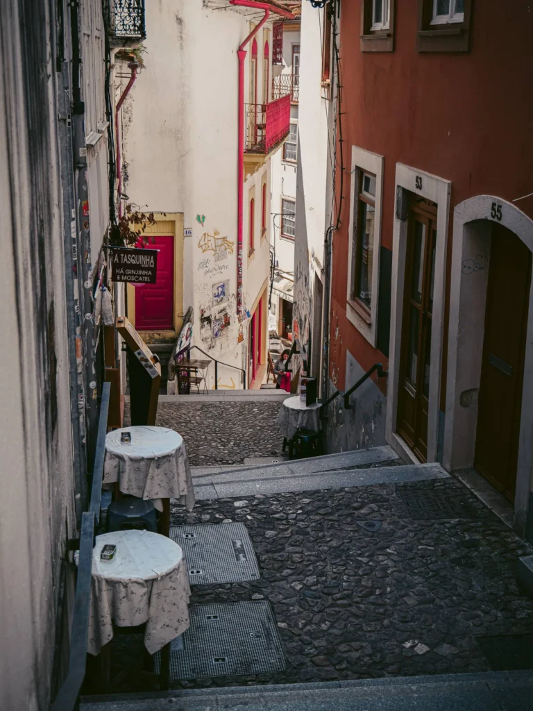 Cobblestone stairway alley in Coimbra with empty café tables and colorful facades, typical urban atmosphere of Portugal.