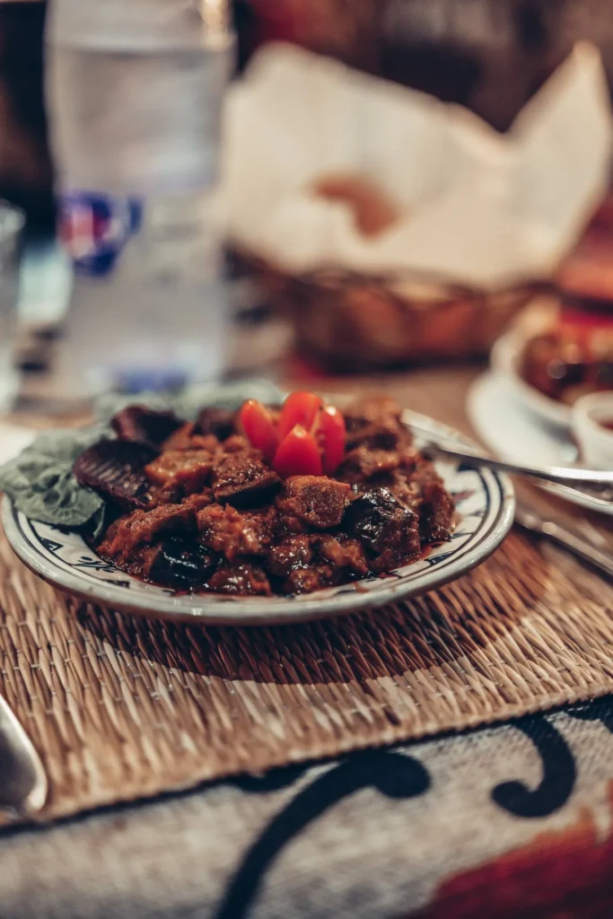 Plate of zaalouk, Moroccan eggplant salad, served on a set table at Adwak restaurant in Essaouira, with a bottle of water and bread in the background.