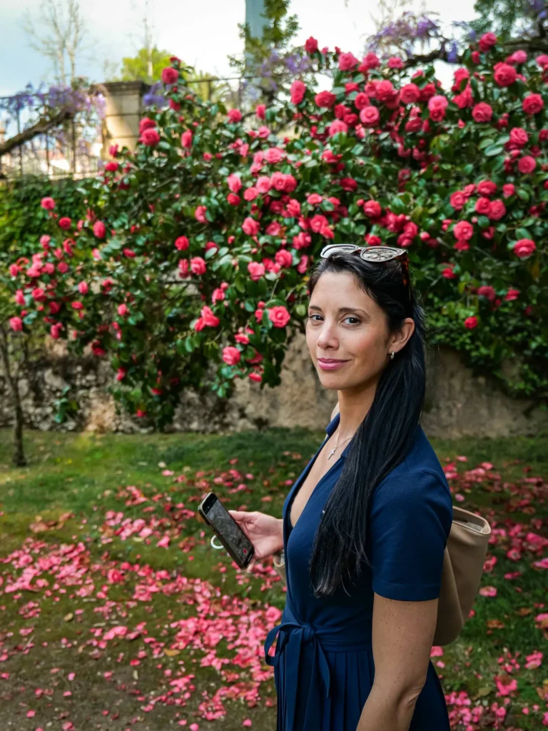 Caroline stands in front of a blooming camellia bush in the Botanical Garden of Coimbra in spring.