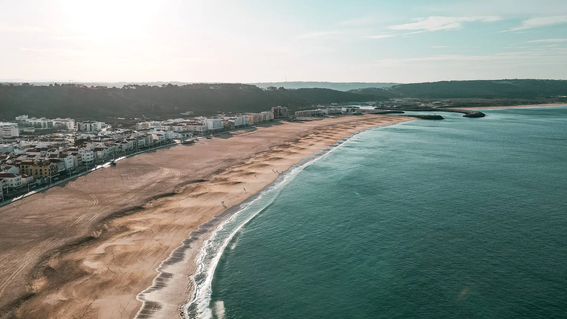 Nazaré beach in Portugal in September 2023, aerial view with the town in the background and the calm Atlantic Ocean.