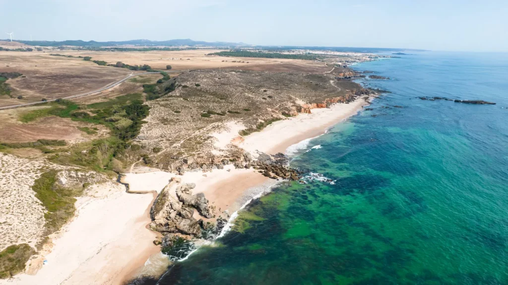 Aerial view of Oliveirinha beach near Porto Covo, in Alentejo, Portugal, showcasing a wild coastline with light sand, rocks, and turquoise waters in June 2026.