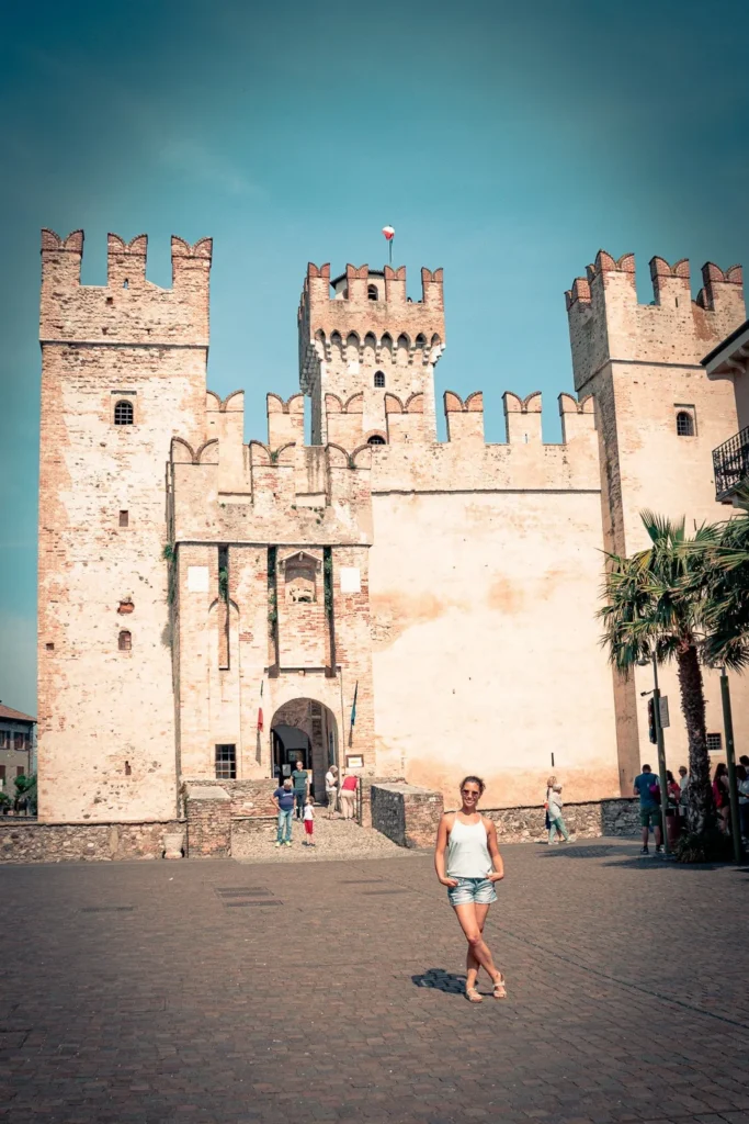 Caroline posing in front of the medieval Scaligero castle in Sirmione under a clear sky