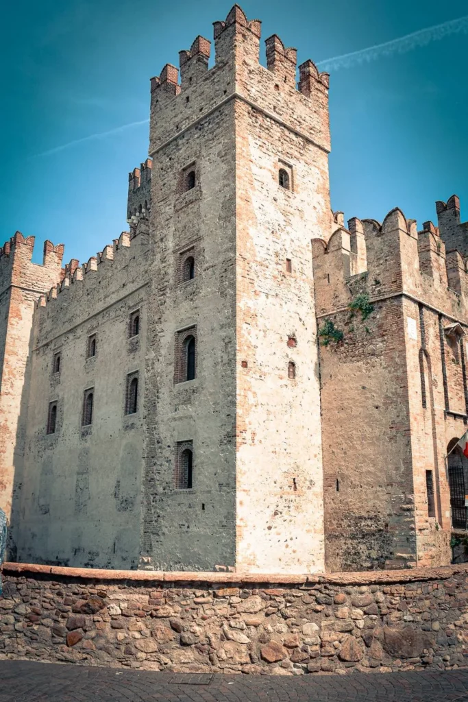 Crenellated stone tower of Sirmione's Scaligero castle under a blue sky