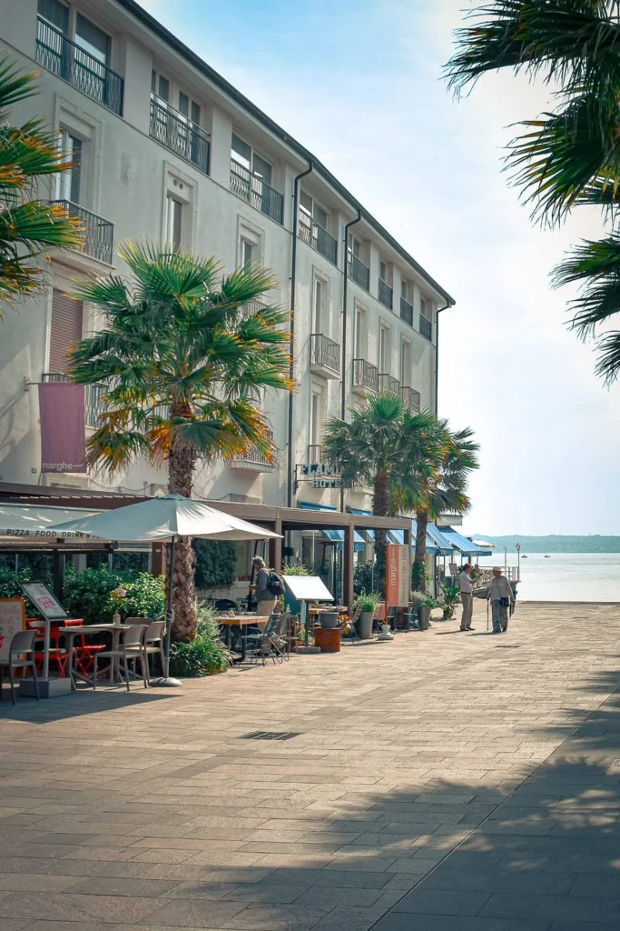 Peaceful stroll along Lake Garda in Sirmione with café terraces and palm trees