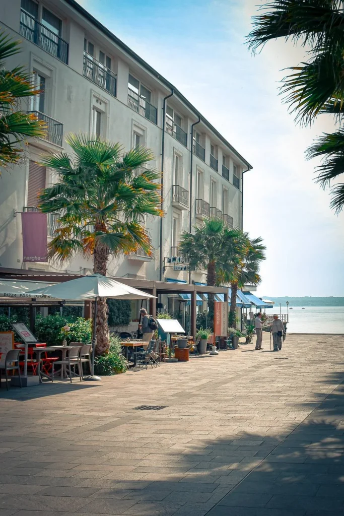 Peaceful stroll in Sirmione, Lombardy with palm trees, café terraces, and lake