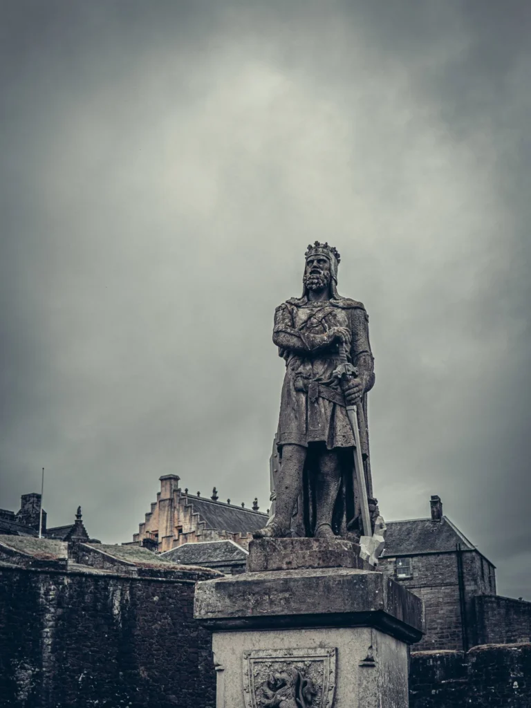 A statue of a medieval king in front of the ramparts of Stirling Castle under a cloudy sky, Scotland, 16 August 2026.