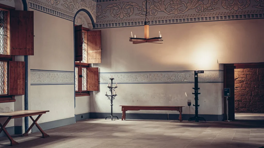 An interior room at Stirling Castle, Scotland, with a wooden bench, candlesticks and leaded windows in natural light.