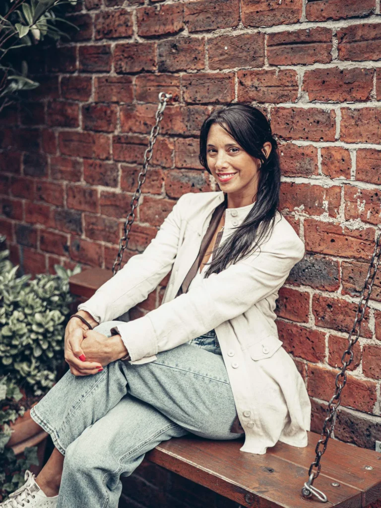 Caroline on a wooden swing in front of a red brick wall, in Glasgow.
