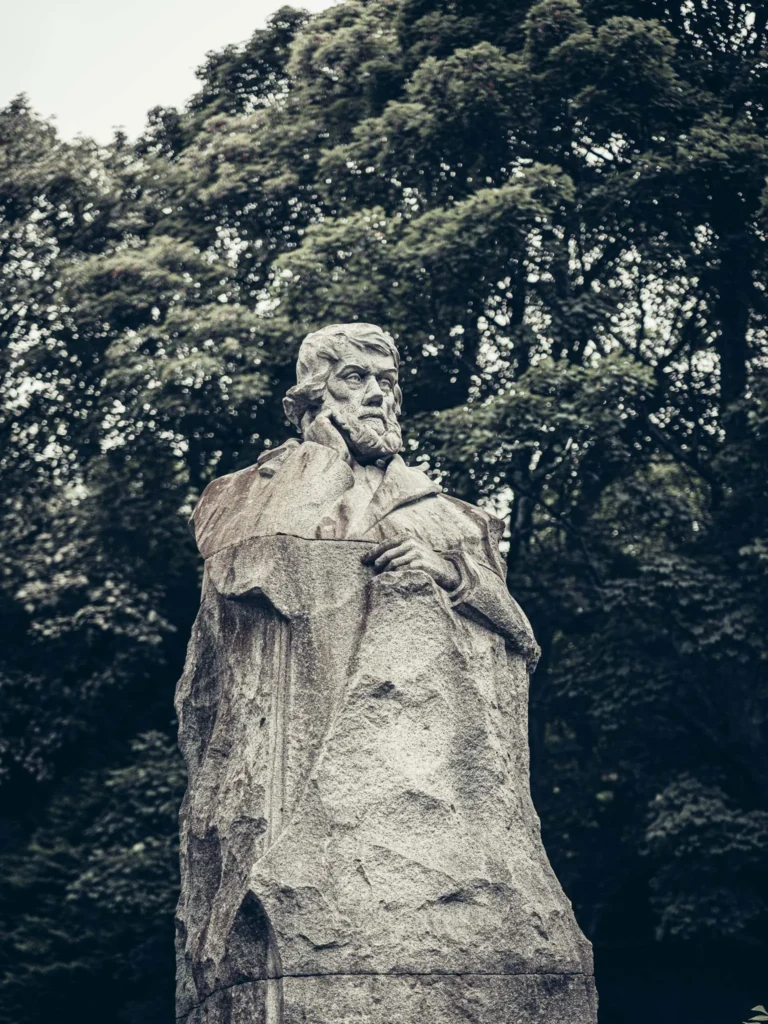 Stone statue of a bearded man in a leafy park in Glasgow. Despite its very mineral architecture, the city appears very green for a large city.